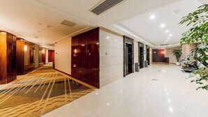 Een moderne hotel lobby met een gepolijste marmeren vloer, houten lambrisering en een grote kamerplant.