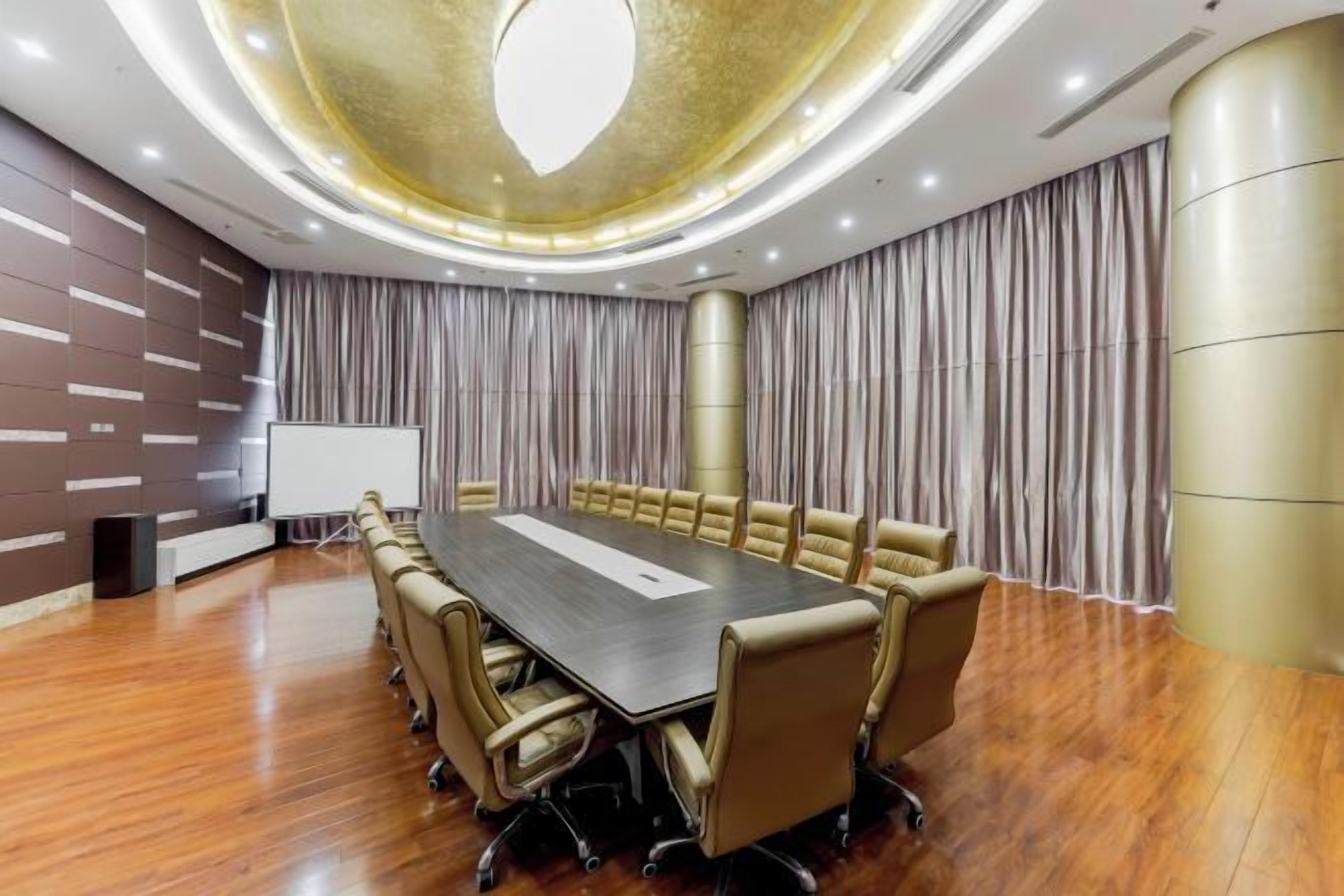 Una sala conferenze con un lungo tavolo, sedie, un proiettore e tende.