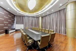 A conference room with a long table, chairs, a projector, and curtains.