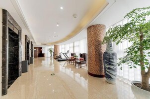 Un hall de hotel con un mostrador de recepción de mármol, zona de estar y una columna grande.