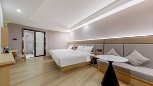 Een moderne hotelkamer met een bed, nachtkastjes, een bank en een klein rond tafeltje.