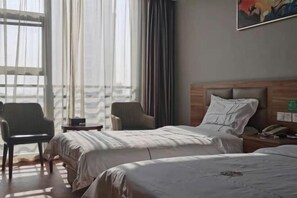 A hotel room with two beds, a chair, a small table, and a painting on the wall. - Yangzhong Zhonghai Hotel (Yangzhong)
