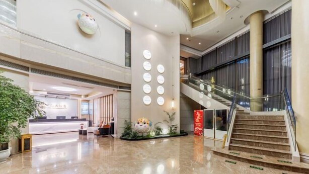 Een moderne hotellobby met een receptiebalie, een trap en een decoratieve wand met ronde verlichting.