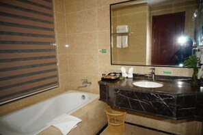 Ein Badezimmer mit einer Badewanne, einem Waschbecken, einem Spiegel und einem Handtuchhalter.