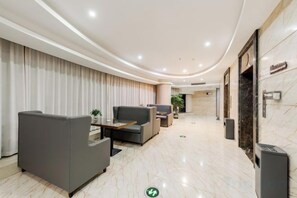 Vestíbulo de hotel con asientos, una recepción y piso de mármol.