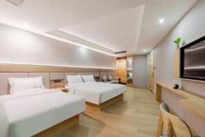 Habitación de hotel con dos camas, televisión, escritorio y una silla.