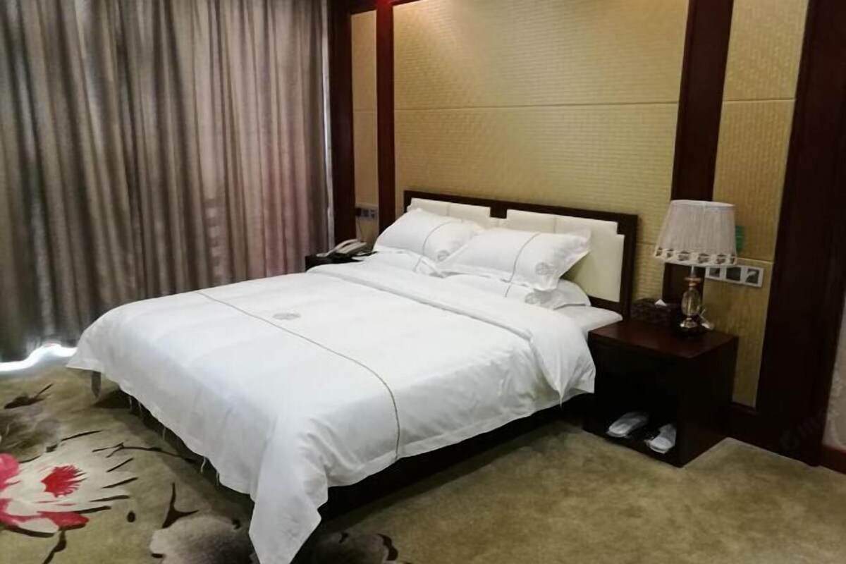 Ein Hotelzimmer mit Bett, Nachttisch, Lampe und Telefon.