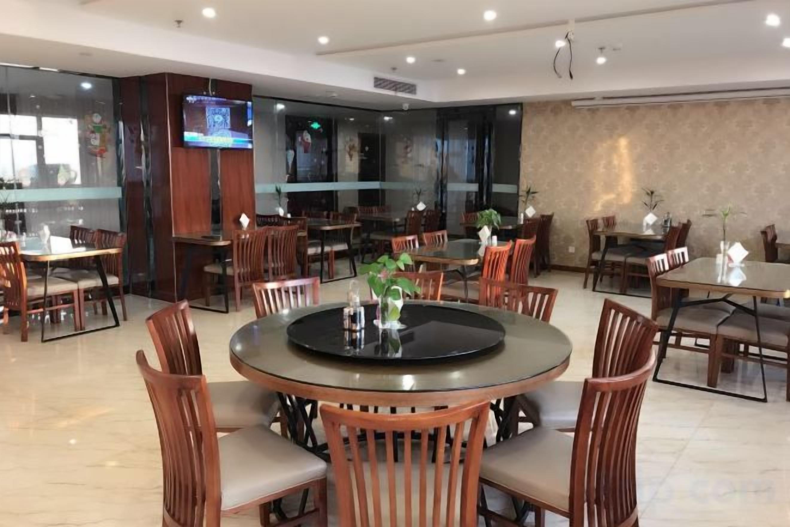 Un comedor de hotel con mesas redondas, sillas de madera y una pantalla de televisión.