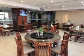 A hotel dining area with round tables, wooden chairs, and a television screen. - Yangzhong Zhonghai Hotel (Yangzhong)