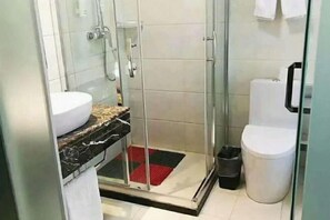 Ein modernes Badezimmer mit einer begehbaren Glasdusche, einer weißen Toilette und einem Waschbecken mit Marmorplatte.