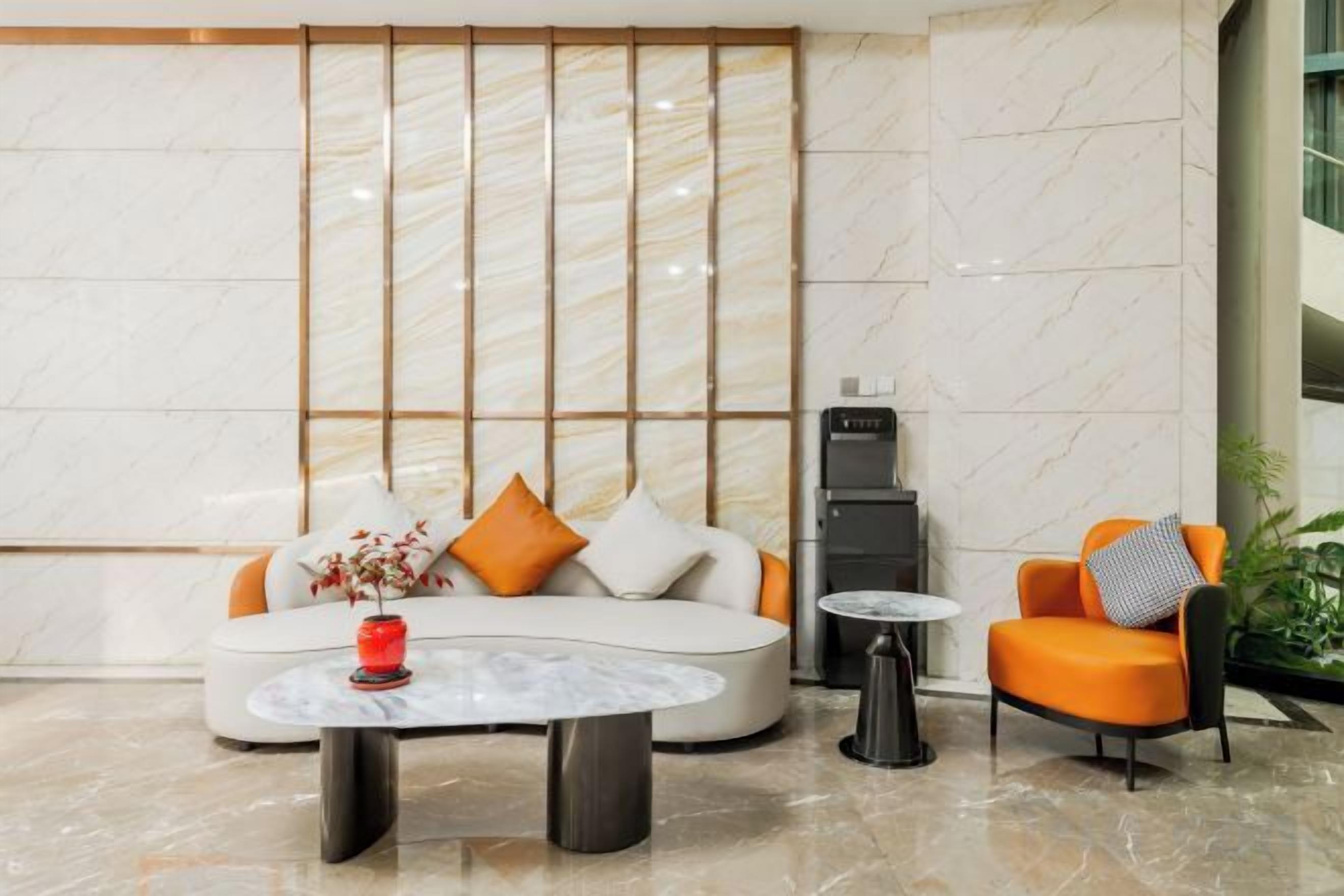 A modern lobby with a sofa, armchair, coffee table, and a fireplace.