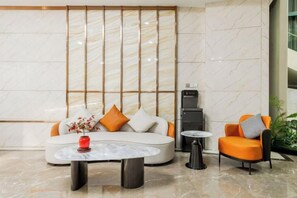 A modern lobby with a sofa, armchair, coffee table, and a fireplace.