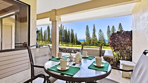 Ein Balkon mit einem Tisch für vier Personen, der einen herrlichen Blick auf Bäume und das Meer bietet.