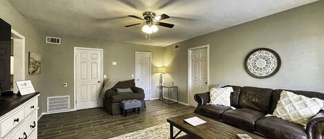 A living room with a ceiling fan, two couches, a coffee table, and a rug.