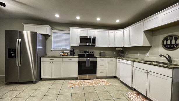 A modern kitchen with white cabinets, stainless steel appliances, and a tiled floor. - Newly remodel home 2BD/2BATH, 15min to dwtn Tulsa. (Owasso)