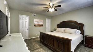 A bedroom with a wooden bed, a ceiling fan, and two doors. - Newly remodel home 2BD/2BATH, 15min to dwtn Tulsa. (Owasso)