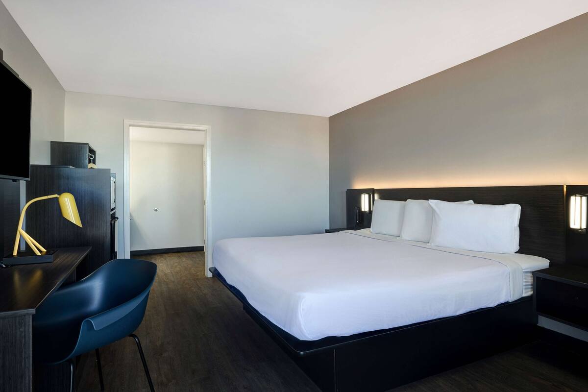 A modern hotel room with a large bed, a desk with a chair, and a flat-screen TV.