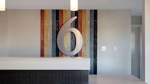 A reception area with a large number '6' sign, a modern counter, and a colorful striped wall. - Motel 6 Bonne Terre, MO (Bonne Terre)