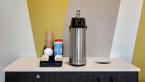 A coffee machine on a counter with disposable cups, a container of creamer, and a tray with coffee pods. - Motel 6 Bonne Terre, MO (Bonne Terre)