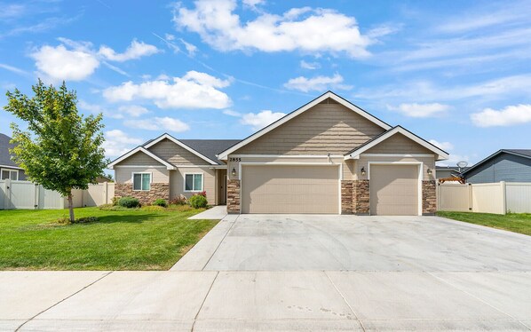 A two-story house with a garage, a stone foundation, and a well-maintained lawn. - Beautiful Family Home (Fruitland)