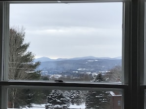 Vista desde una ventana, cielo despejado y montañas a lo lejos.