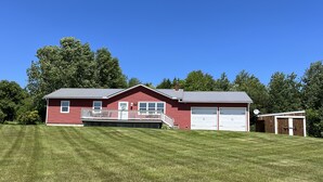 A red house with a white porch, two garage doors, and a small shed. - Spectacular views and close to three ski areas; Stowe, Smuggler’s  and Jay Peak. (Hyde Park)