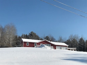 Une maison rouge avec un toit enneigé et un garage.