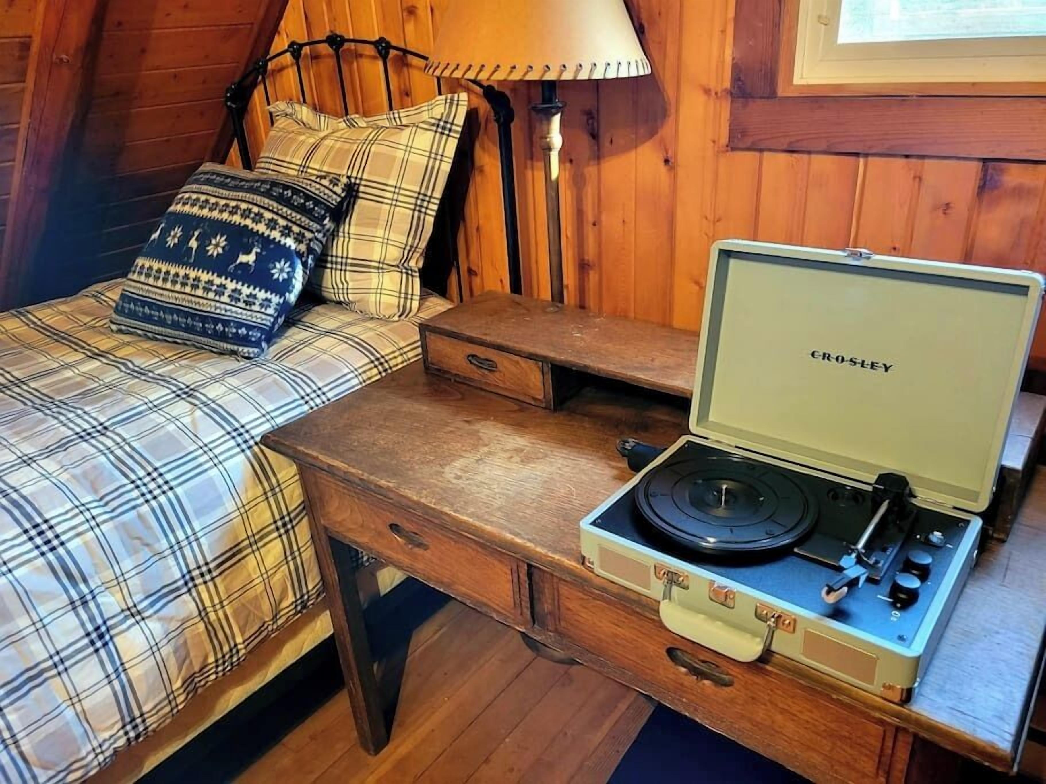 Una habitación acogedora con una cama, un escritorio de madera y una radio Crosley.