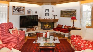 A cozy living room with a fireplace, red and white checkered sofas, a flat-screen TV, and various wall decorations. - Marie-Soleil Sud by Interhome (Saanen)