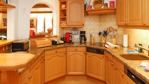 A kitchen with wooden cabinets, a dishwasher, a coffee maker, and a toaster. - Marie-Soleil Sud by Interhome (Saanen)