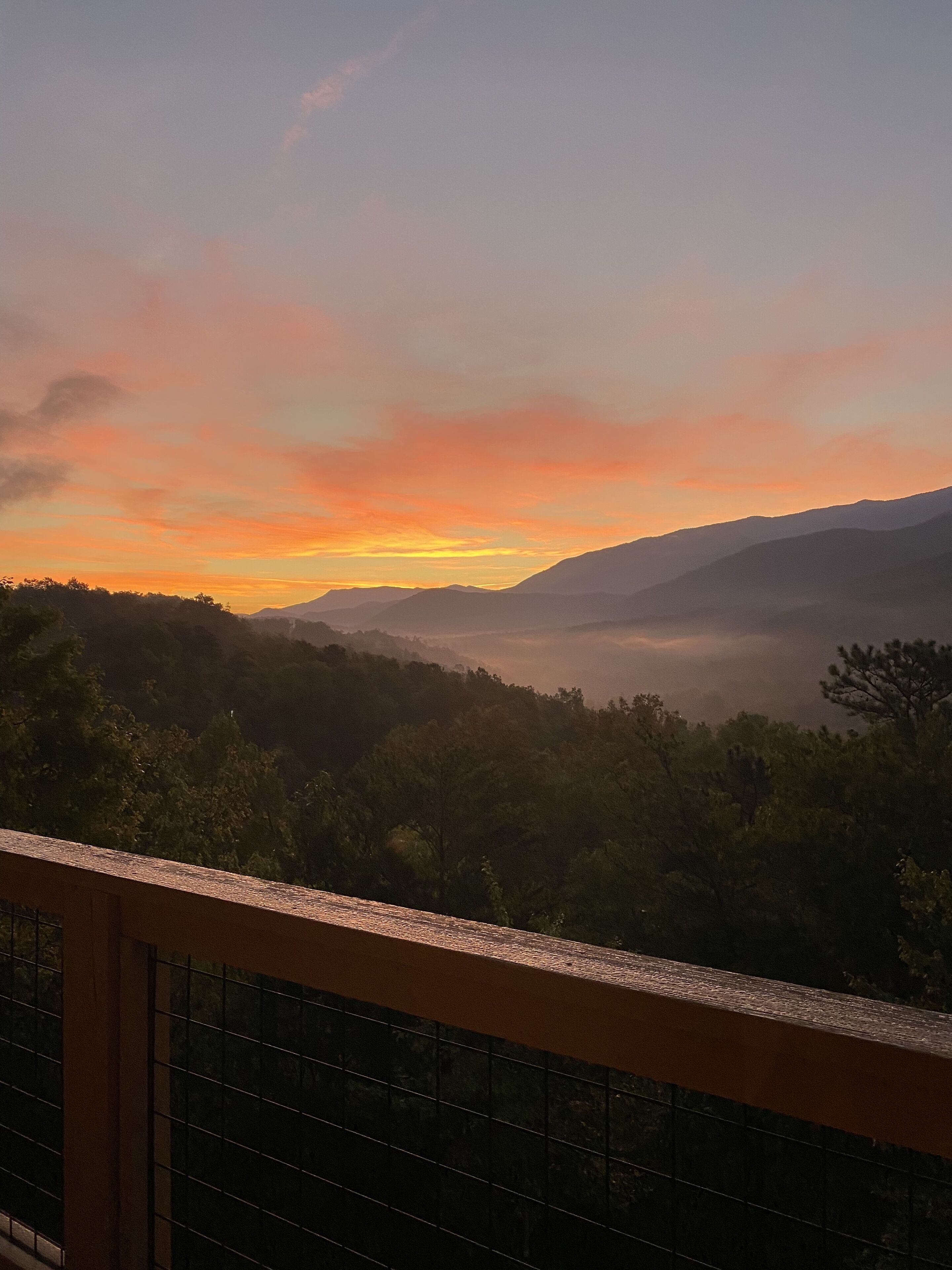A view from a balcony overlooking a mountainous landscape during sunset.