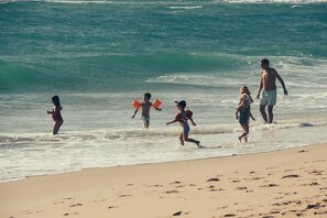 Une scène de plage où l’on voit des personnes se promener le long du rivage.