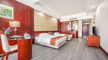 A hotel room with a desk, two beds, a TV, and a mirror.