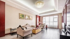 A spacious living room with a chandelier, sofas, a coffee table, and a television. - Jinyuan Hotel (Hui County)