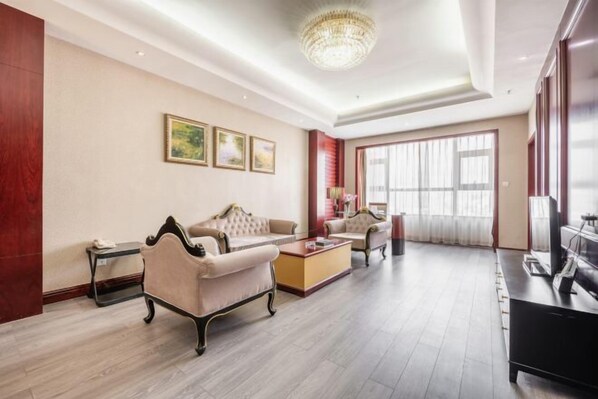 Un amplio salón con candelabro, sofás, una mesa de centro y televisor.