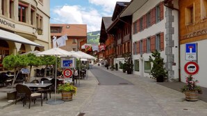 A street with outdoor seating, a 'Zone' sign, and a 'No Parking' sign.