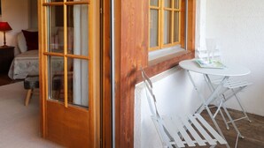 A room with a wooden door, a small white table with chairs, and a bed with a floral bedspread.