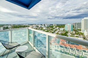 A balcony with a glass railing overlooking a cityscape. - 18th Floor, Snowbird-Friendly Condo with Shared Pool, Ocean View, and Fast WiFi (Fort Lauderdale)