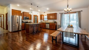 Cocina amplia con armarios de madera, electrodomésticos de acero inoxidable y una isla central con taburetes.