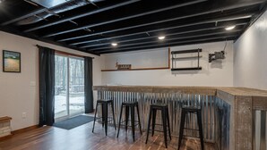 Una zona de bar con tres taburetes, un mostrador de madera y un letrero que dice 