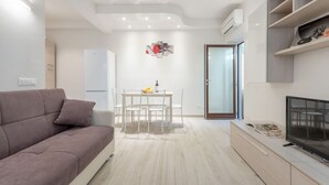 Ein modernes Wohnzimmer mit einer Couch, einem Esstisch und einem Fernseher.
