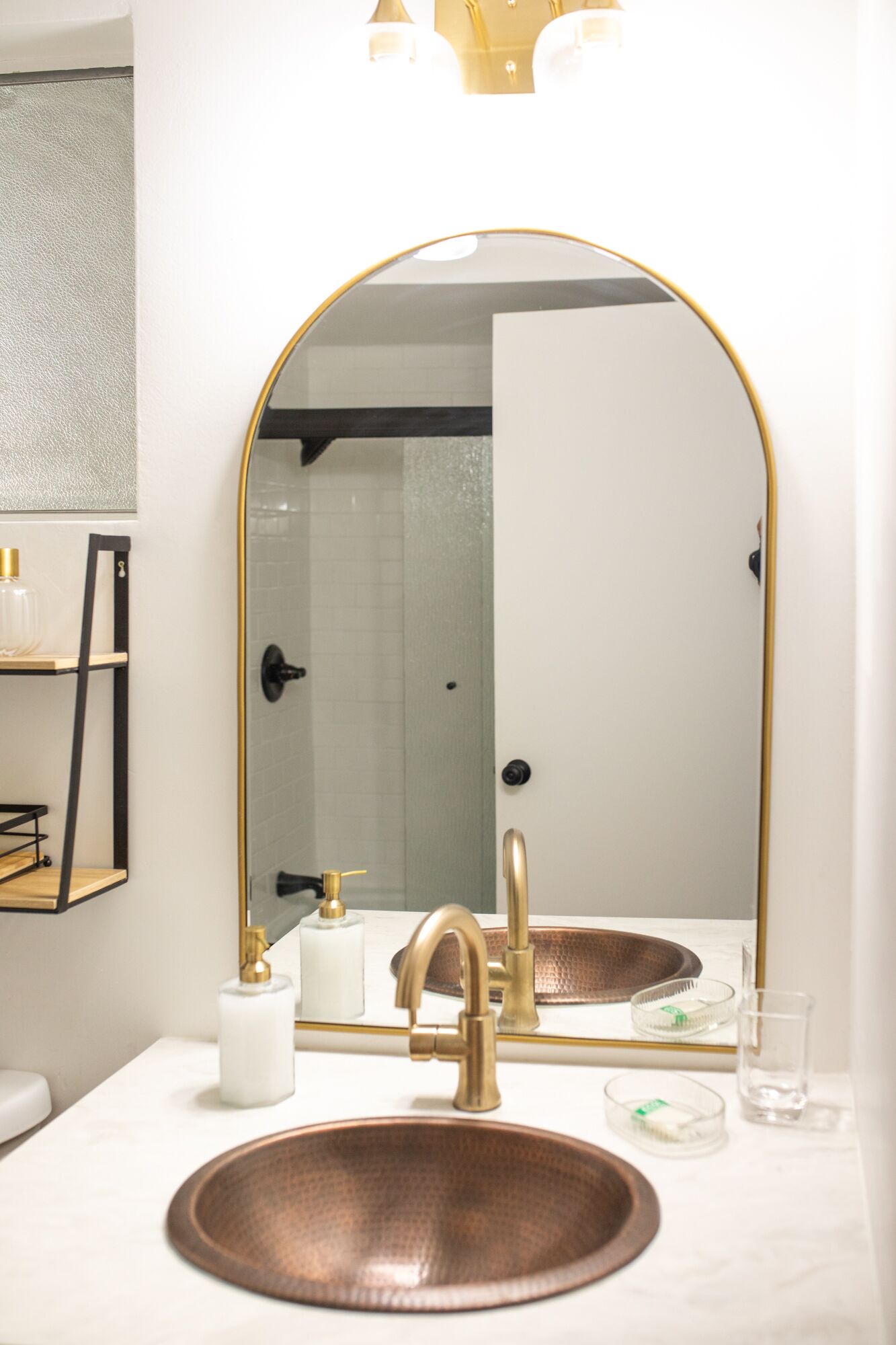 Un bagno con un lavandino in rame, uno specchio con cornice dorata e un ripiano bianco.