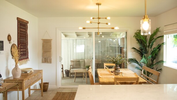 A modern kitchen with a marble countertop, wooden cabinets, and a hanging light fixture.