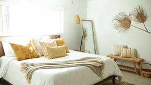 A bedroom with a large bed, a bedside table, a mirror, and a window.