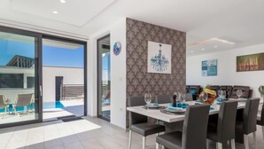 A modern dining area with a large table set for six, surrounded by chairs. - Apartment Albi by Interhome (Rijeka)