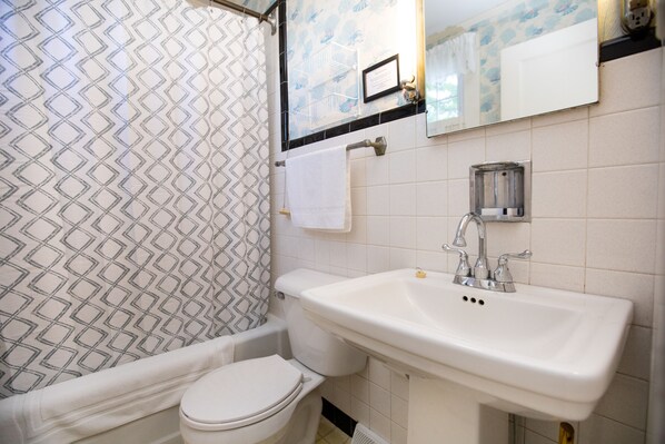 A bathroom with a white toilet, a sink, and a shower curtain with a geometric pattern.