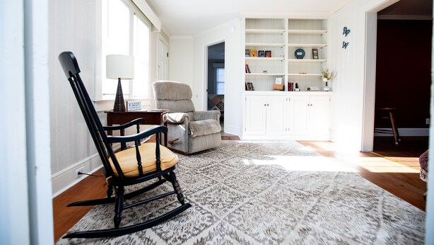 A room with a rocking chair, a bookshelf, and a patterned rug. - Worsham Farmhouse (Farmville)