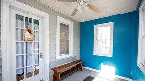 A room with a wooden bench, a ceiling fan, and a door with a rooster decoration. - Worsham Farmhouse (Farmville)