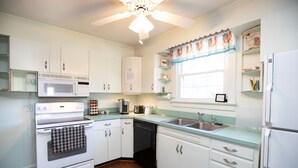 A kitchen with white cabinets, a microwave, an oven, a dishwasher, and a sink. - Worsham Farmhouse (Farmville)