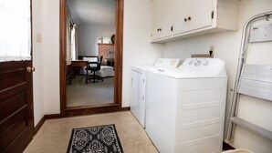 A laundry room with a washing machine, a dryer, and a cabinet. - Worsham Farmhouse (Farmville)